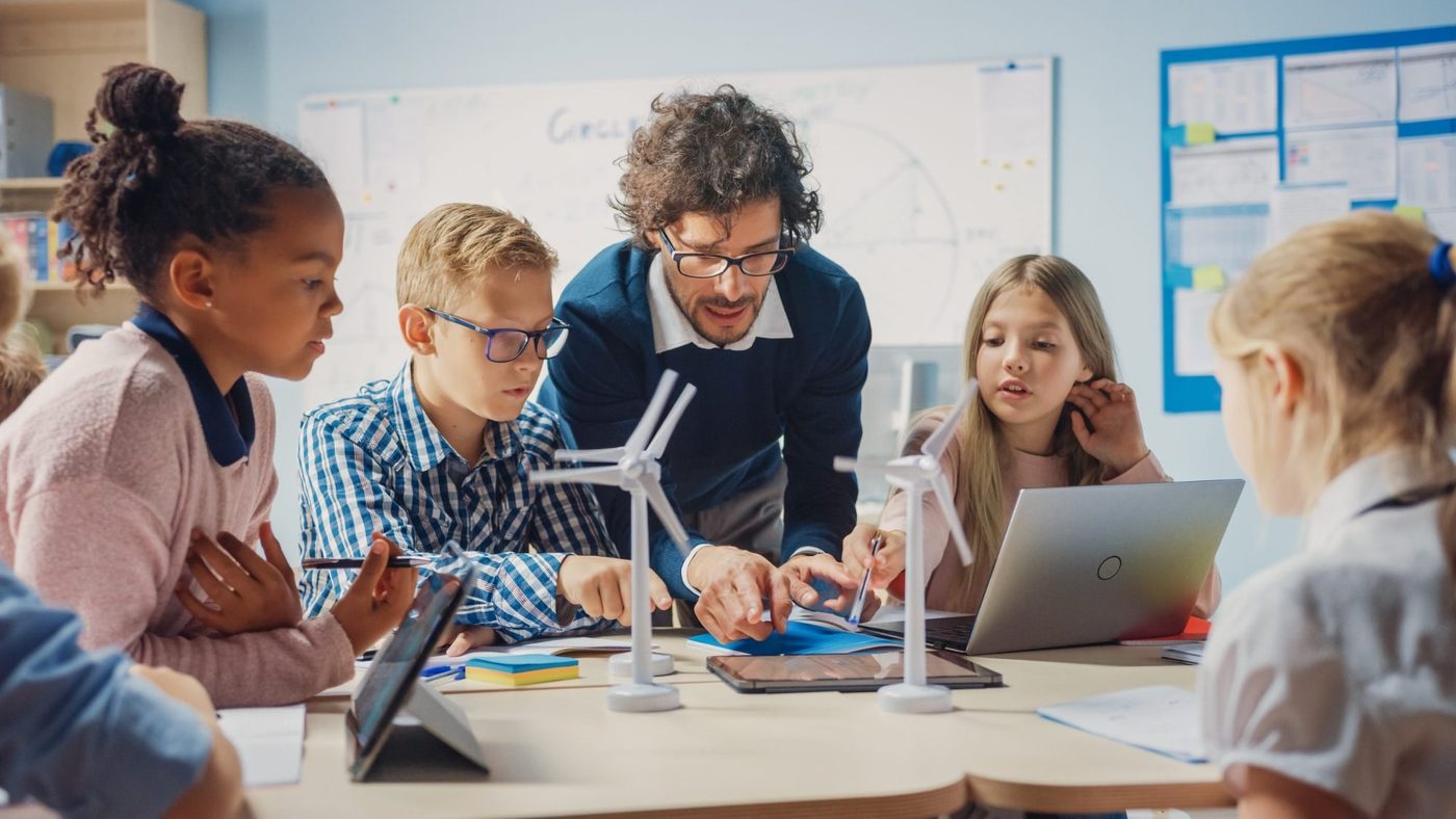 Professor e crianças em projeto social de educação e tecnologia